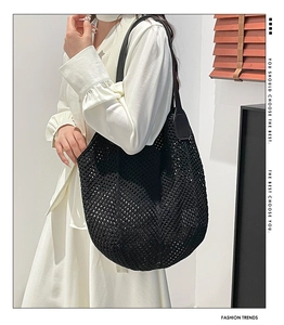 Detail of black hollow knit tote bag showing intricate crochet texture and leather handle