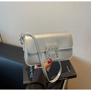 Close-up of silver rhinestone square buckle on stylish metallic faux leather handbag