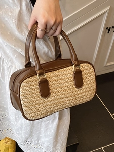 Straw woven boston handbag with brown PU leather trim held by a model for summer style