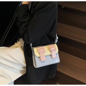 Macro detail of macaron-colored crossbody bag featuring yellow flap and pink buckle straps