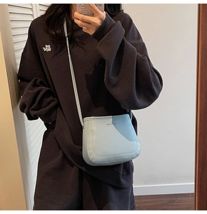 Close-up of a light blue pebble leather bucket bag shown in a casual mirror selfie