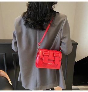 Detailed back view of a model wearing a vivid red leather satchel with decorative buckles
