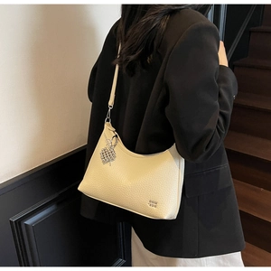 Detail view of cream hobo bag with pebble leather texture and silver heart charm pendant