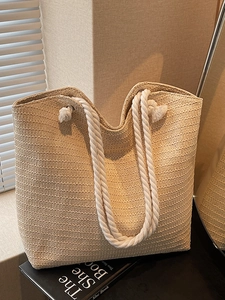 Large beige woven straw tote bag with white cotton rope handles for summer beach use