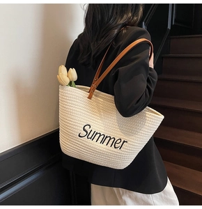 Detail of woven straw tote bag with Summer embroidery and brown leather handle