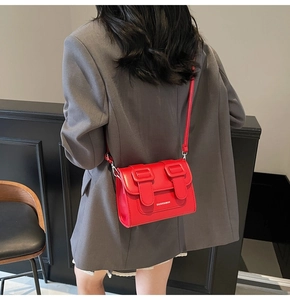 Rear view of a model wearing a chic red leather satchel bag with silver hardware
