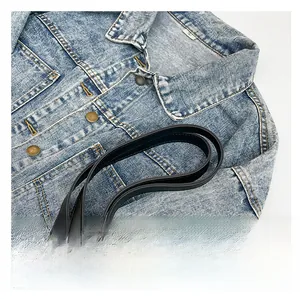 Macro shot of white woven tote bag with a black leather strap and denim jacket detail