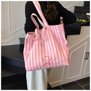 Detail of pink striped canvas tote bag with lucky dog embroidery and brand woven label