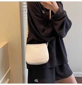 Detail of white lychee pattern crossbody bag featuring a unique woven shoulder strap