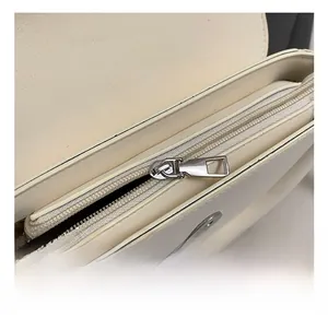 Détails du sac à main en cuir blanc crème montrant des coutures fines et ferrures argentées