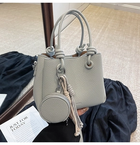 Dettaglio borsa a secchiello in pelle celeste con motivo litchi e nappa a frange intrecciate