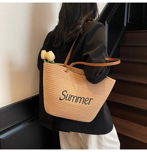 Detail of straw tote bag with Summer embroidery and brown leather shoulder straps
