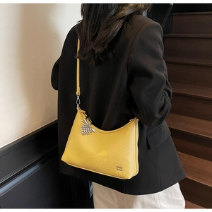 Detail shot of yellow leather crossbody bag with lychee texture and silver heart charm