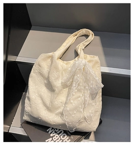 Detailed macro of cream lace floral embroidery and bow tie decoration on the tote bag