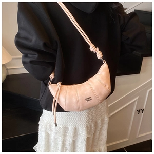 Detail of pink half-moon crossbody bag with quilted pleats and knotted strap on model