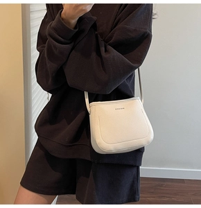Detail of white litchi pattern leather bucket bag with brand logo and slim shoulder strap