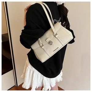 Close-up of cream textured leather shoulder bag with silver clasp and buckle details