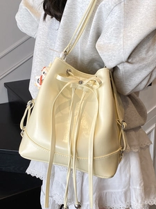 Cream yellow bucket bag with drawstring bow detail and cute cartoon pendant charm