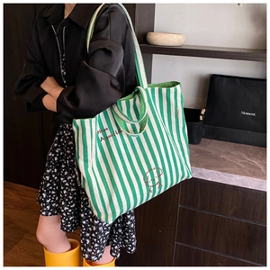 Detail view of large green and white striped canvas tote bag with dog graphic and text