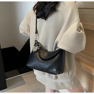 Detail view of black litchi pattern leather crossbody bag with silver heart charm