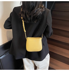 Detail of yellow lychee leather mini bucket bag with a stylish thick woven shoulder strap