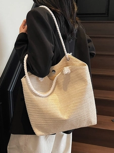 Minimalist large woven straw tote bag with white rope handles for summer beach use