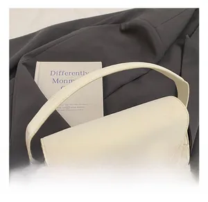 Détail d'un sac bandoulière blanc crème avec un grand nœud sur un blazer gris