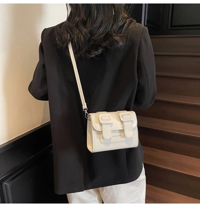 Chic ivory faux leather crossbody bag with double buckle flap shown on model side view