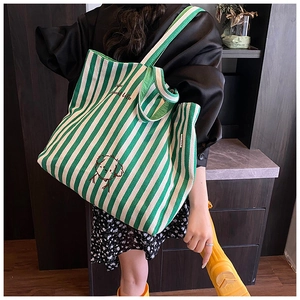 Detailed close-up of green and white striped canvas tote bag with embroidered puppy pattern