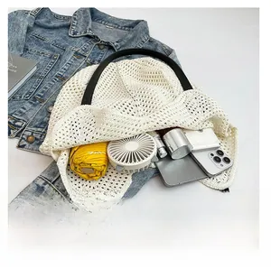 Top-down view of a spacious white knit tote bag filled with daily essentials on a denim jacket