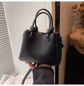 Dettaglio borsa a secchiello in pelle martellata nera con manici e nodi decorativi