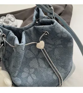Detail of blue denim floral bucket bag with heart-shaped silver metal drawstring slider