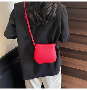 Detail of red lychee grain leather bucket bag with handcrafted woven strap attachment