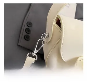 Détail montrant le crochet en métal argenté et la bandoulière en cuir du sac de selle