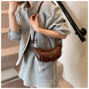 Detail of a brown half-moon shoulder bag with a stylish knot and drawstring detail