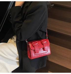 Detail of red vintage leather satchel with double straps and silver metal buckles