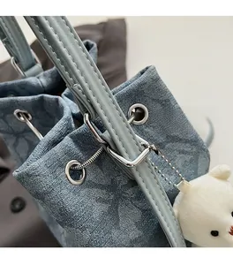Close-up of light blue denim bucket bag showing premium silver hardware and bear charm