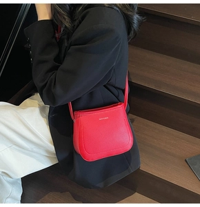 Close-up of a red lychee pattern crossbody bucket bag worn by a model in a dark setting