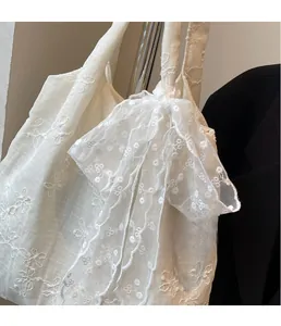 Detailed view of white floral lace embroidery and sheer scarf accessory on a tote bag