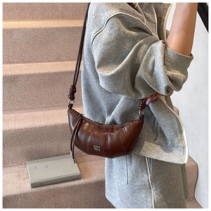 Detail of dark brown croissant bag with quilted pleats and knotted shoulder strap