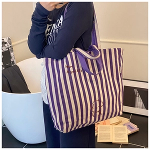 Detail showing high-capacity striped canvas tote bag with embroidery and dual handles