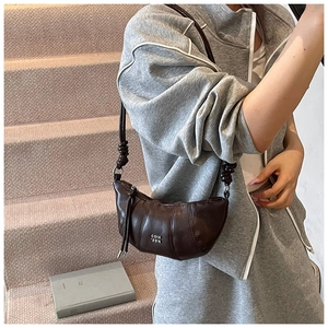 Detail of a dark brown half-moon hobo bag with thick knotted strap and stylish curved seams