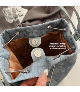 Close-up of denim bucket bag interior featuring a magnetic snap closure and zipper pocket