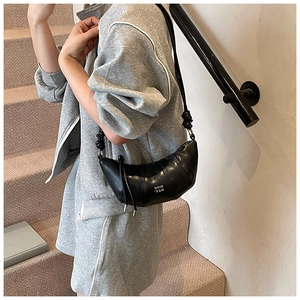 Close-up of black crescent bag featuring a knotted shoulder strap and logo detail
