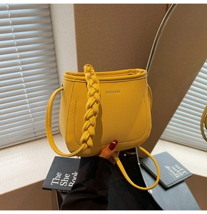 Detail of yellow lychee leather bucket bag with braided handle and silver lettering