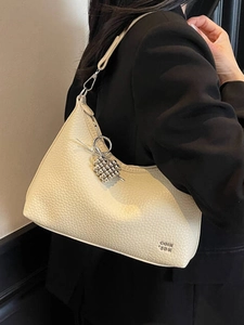 Minimalist beige pebble leather square shoulder bag with heart bead charm on black blazer