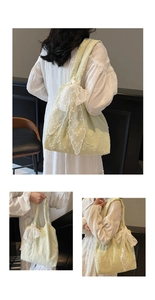 Close-up of floral embroidery and white lace bow detail on a green canvas tote bag