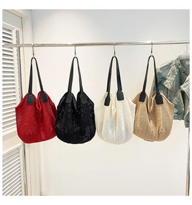 Detail of four colorful knit tote bags with black leather handles hanging on a rack