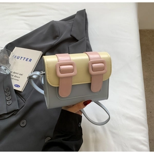 Detail of multi-color macaron crossbody bag with leather buckle straps on gray blazer