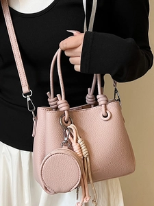 Secchiello minimalista rosa chiaro in pelle con nappa intrecciata e ciondolo portamonete